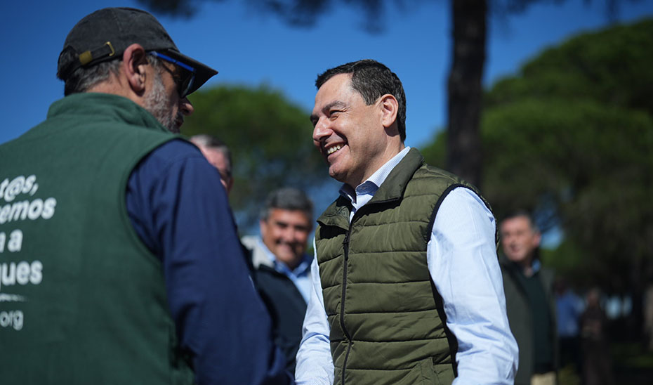 Juanma Moreno conversa con uno de los trabajadores que presta su servicio en la plantaci&oacute;n de &aacute;rboles en el paraje de 'Las Pe&ntilde;uelas'.