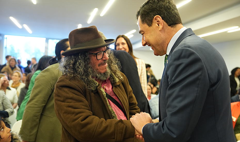 Juanma Moreno, presidente de la Junta, saluda al m&uacute;sico sevillano Raimundo Amador durante el acto.